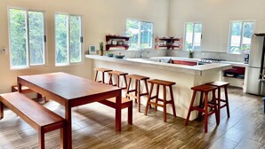 Une cuisine moderne avec un îlot central, des tabourets en bois et une table à manger.
