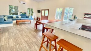Un salon moderne avec un canapé bleu, une table basse en bois et un coin cuisine doté d’un grand îlot central et de tabourets de bar.