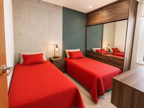 A bedroom with two beds, a nightstand, a mirror, and a wooden dresser.