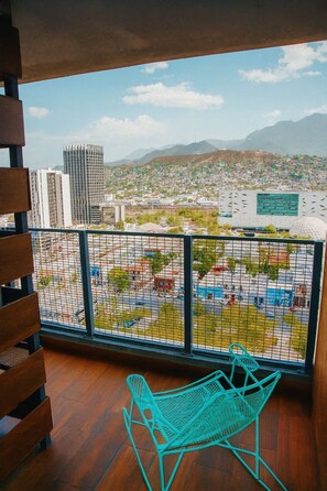 A balcony with a view of a cityscape, including buildings and mountains.