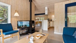 A cozy cabin interior with a wooden interior, a fireplace, a dining area, and a kitchen. - "Deni" - 800m from the sea by Interhome (Nexø)