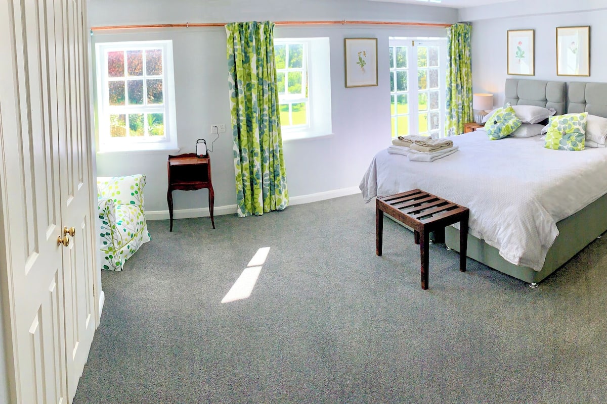 A bedroom with a bed, bedside tables, a bench, a dresser, and a door.