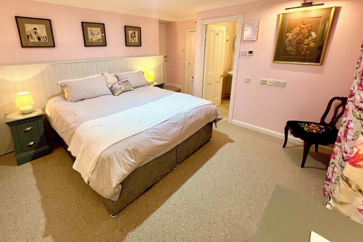 A bedroom with a bed, nightstands, a chair, and a door.