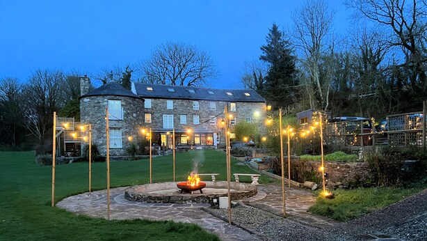 A stone building with a circular patio and a fire feature. - The Mill House (Ballasalla)