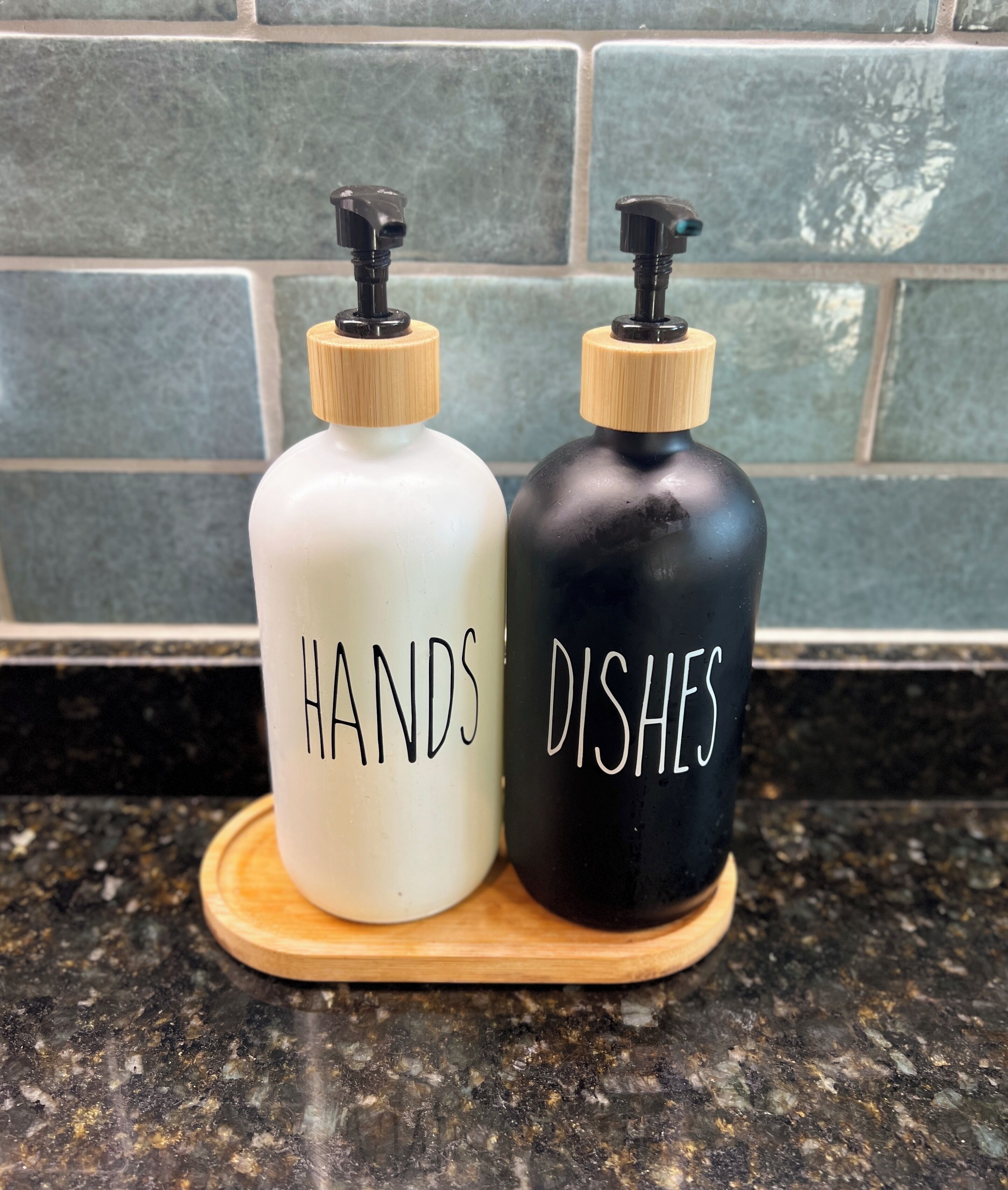 Two soap dispensers labeled "HANDS" and "DISHES" on a wooden tray.