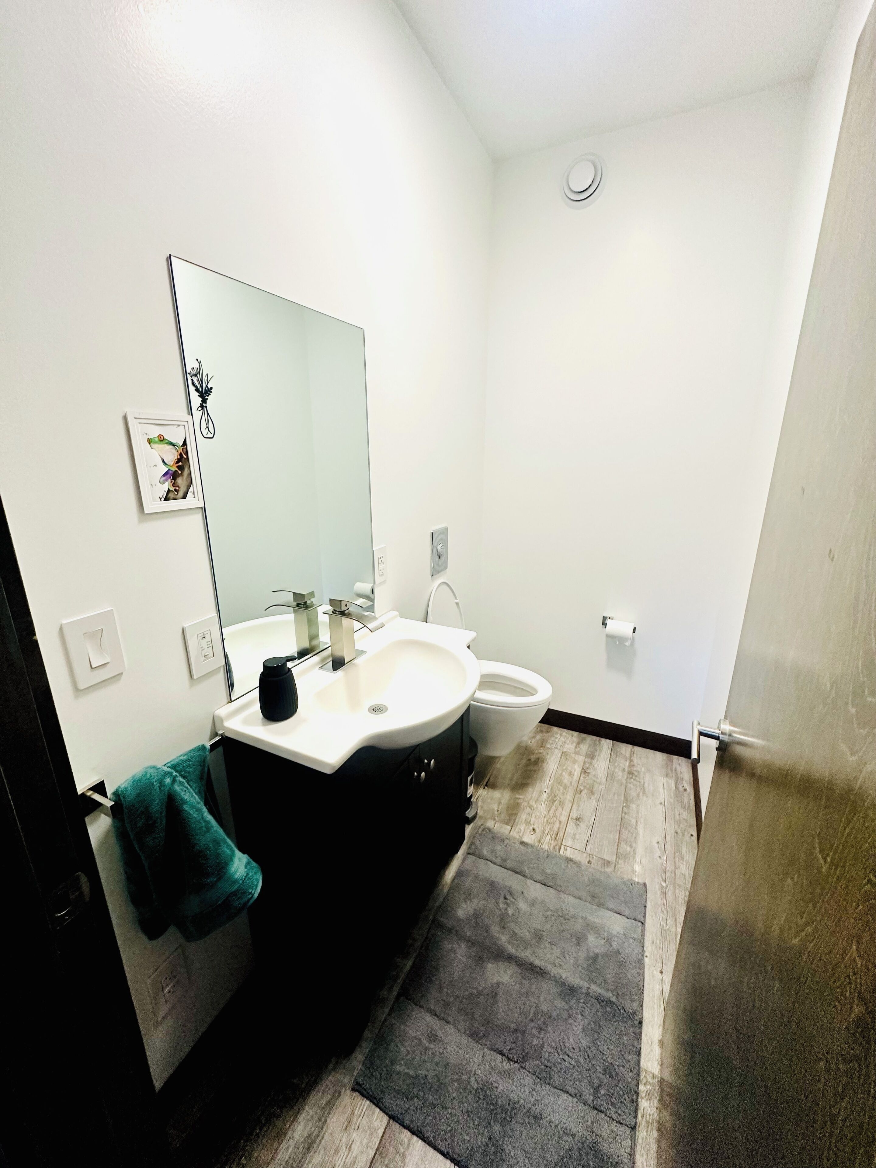 A bathroom with a white sink, a mirror, a toilet, and a towel hanging on the wall.