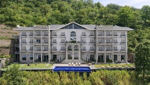 Un hôtel à plusieurs étages doté d’une cour intérieure, d’une piscine et surplombant une colline verdoyante.