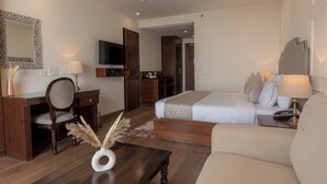 Une chambre d’hôtel comprenant un lit, un canapé, un bureau avec une chaise, une télévision et un miroir.