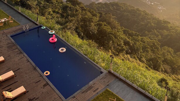Une piscine dotée de chaises longues et offrant une vue sur un paysage montagneux.