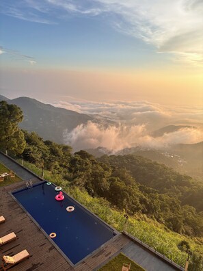Une piscine dotée de chaises longues et offrant une vue sur un paysage montagneux.