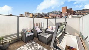 A rooftop terrace with wicker furniture, a patterned rug, and a potted plant. - Family size Penthouse in Covent Garden w/roof garden & additional small patio (London)