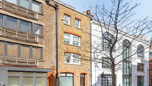 A multi-story building with a mix of brick and modern facade, large windows, and a tree in front. - Family size Penthouse in Covent Garden w/roof garden & additional small patio (London)