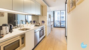 Une cuisine moderne dotée d’appareils électroménagers en acier inoxydable, d’un évier à deux bacs et d’une grande fenêtre offrant une vue sur la ville.