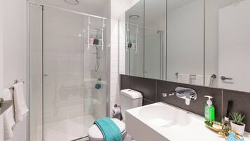 A modern bathroom with a glass-enclosed shower, a white sink, and a mirror above the sink.