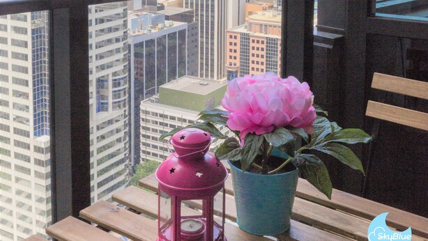 Un balcon donnant sur une vue de la ville, une lanterne rose et une plante en pot.