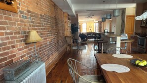 A spacious kitchen with wooden flooring, a brick wall, and a dining area with a wooden table and chairs. - Stunning river view loft in Wabasha near Eagle Center (Wabasha)