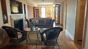 A cozy living room with a fireplace, a sofa, and two wicker chairs around a small table. - Stunning river view loft in Wabasha near Eagle Center (Wabasha)
