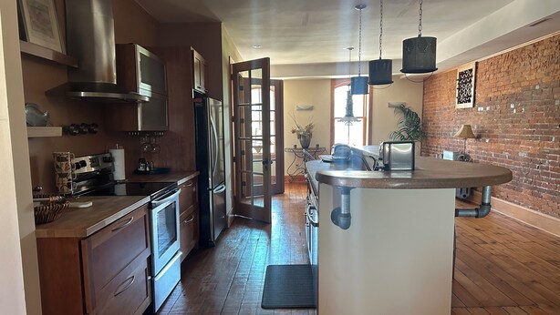 A modern kitchen with wooden cabinets, stainless steel appliances, and a central island. - Stunning river view loft in Wabasha near Eagle Center (Wabasha)