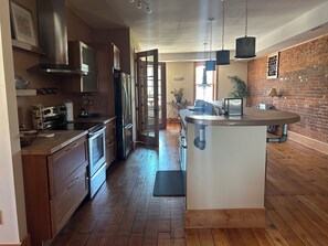 A modern kitchen with wooden cabinets, stainless steel appliances, and a central island. - Stunning river view loft in Wabasha near Eagle Center (Wabasha)