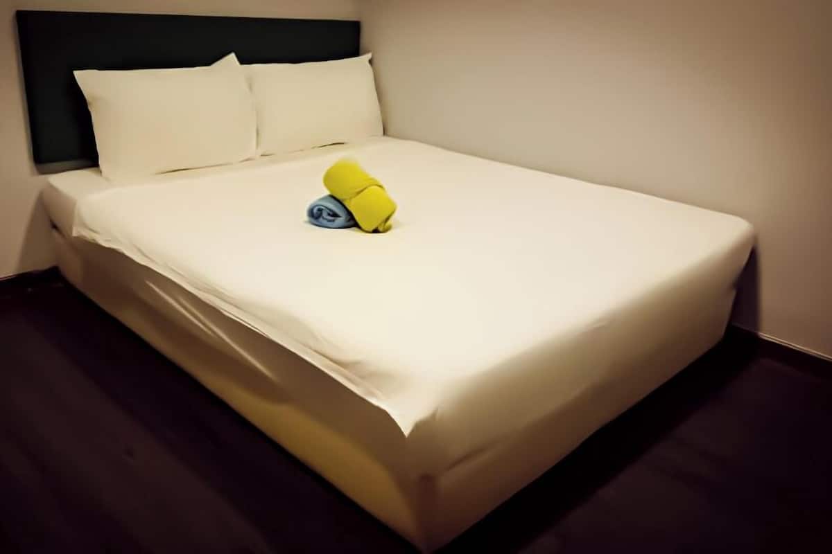 A neatly made bed with white sheets and pillows, a dark headboard, and a small yellow object on the bed.