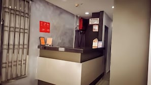A reception desk with a metal grille, a red sign, and a sign for 'OILARANG'. - Moon Night Hotel (Batu Caves)
