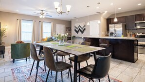 A modern kitchen with a central island, stainless steel appliances, and a dining area with a table and chairs.