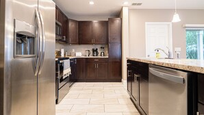 A modern kitchen with stainless steel appliances, dark wooden cabinets, and a marble countertop.