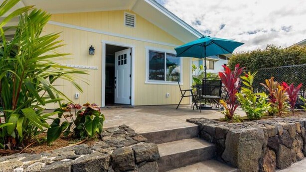 A yellow building with a covered patio area, stone steps, and outdoor seating.