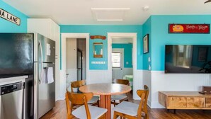 A kitchen with a refrigerator, dishwasher, and wooden dining table with chairs.