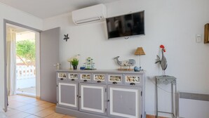Ein Wohnzimmer mit einem grauen Schrank, der Muscheln zeigt, einem Wand-Fernseher und Dekorationsgegenständen, darunter ein Hahn und eine Lampe.
