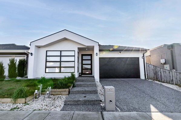 Een modern gelijkvloers huis met garage, voortuin en een grindpad, plus een brievenbus.