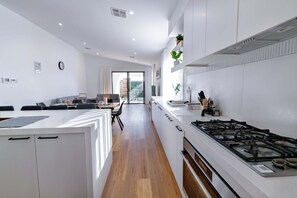 Une cuisine moderne dotée d’un îlot central, de meubles blancs et d’une cuisinière à gaz.