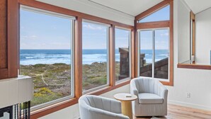 A room with large windows, a view of the ocean, and two chairs.