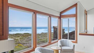 A room with large windows, a view of the ocean, and two chairs.