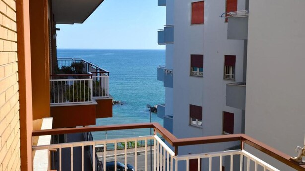 A high-rise building with balconies overlooking a body of water.