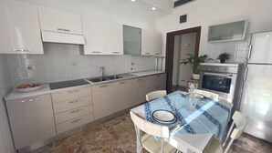 A modern kitchen with white cabinets, a marble countertop, and a dining area with a table set for two.
