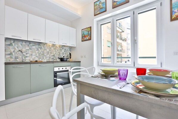 A modern kitchen with white cabinets, a tiled backsplash, and a dining area with a table set for two.
