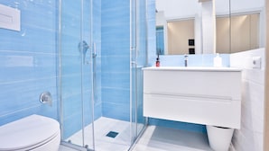 A modern bathroom with a glass shower enclosure, a white toilet, and a vanity with a mirror. - GuestHost - Studio Apartment Gem: Compact Comfort Redefined (Salerno)