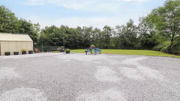 Ein Kiesparkplatz mit einem blauen Picknicktisch und Topfpflanzen.