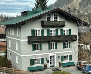 A multi-story building with a balcony, green shutters, and a door with a small porch area. - Villa Anna Kitzbühel design apartments (Kitzbuhel)