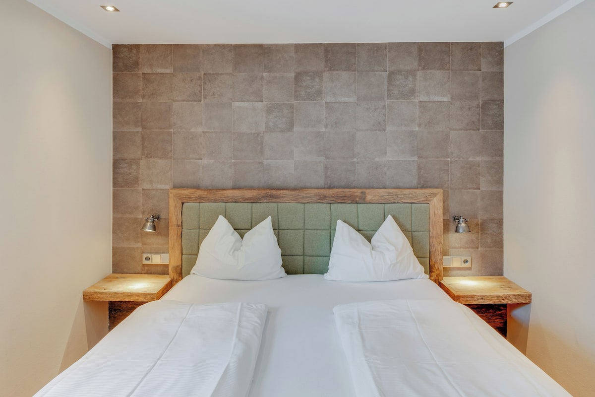 A double bed with a wooden headboard and two bedside tables with lamps.