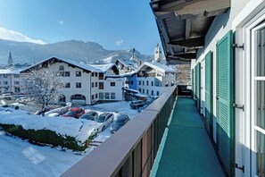A snow-covered hotel with a balcony overlooking a parking area and a mountain view. - Villa Anna Kitzbühel design apartments (Kitzbuhel)