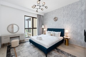 Ein modernes Hotelzimmer mit einem großen Bett, einem Schreibtisch, einem runden Spiegel und Blick ins Freie.