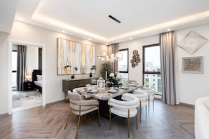 A modern dining area with a marble table, white upholstered chairs, and a chandelier. - Modern 4BR w/ Full Burj Al Arab View & Pvt Rooftop (Dubai)