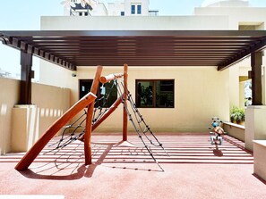 Une aire de jeux avec une structure d’escalade en bois et une trottinette.