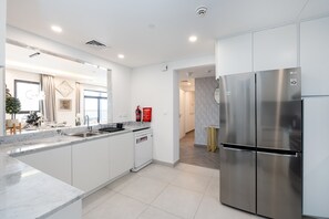 A modern kitchen with white cabinetry, a stainless steel refrigerator, and a built-in dishwasher. - Modern 4BR w/ Full Burj Al Arab View & Pvt Rooftop (Dubai)
