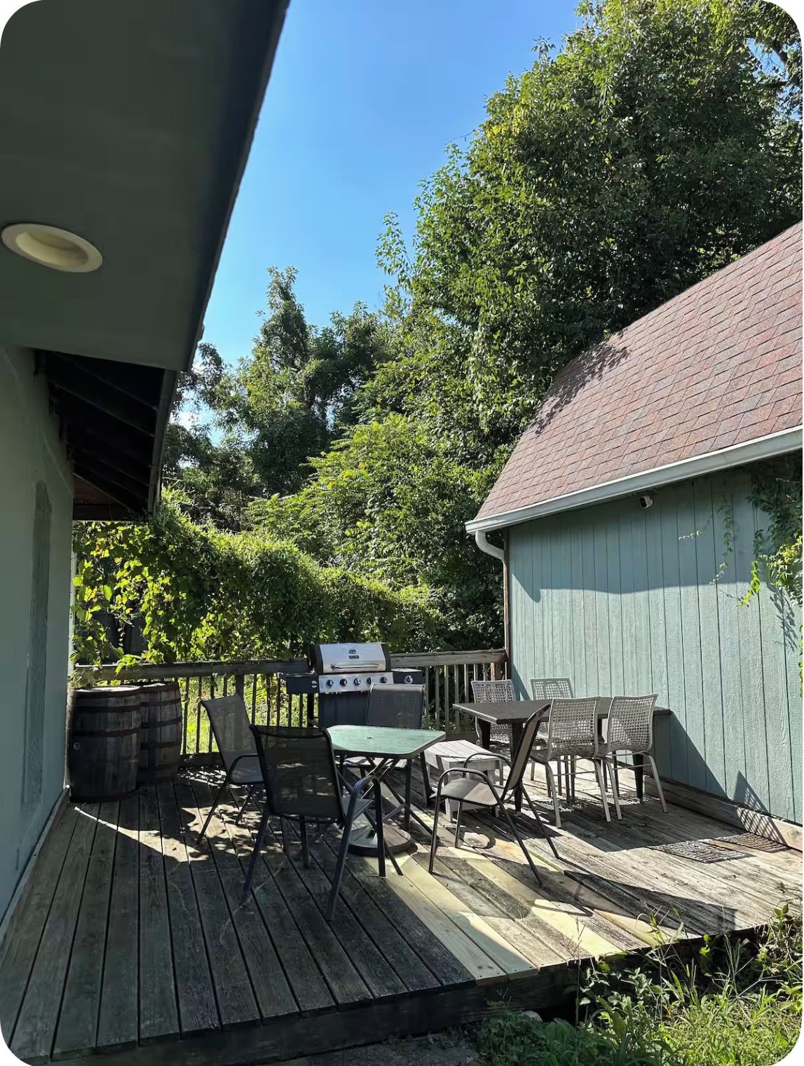 A wooden deck with outdoor furniture and a barbecue grill.