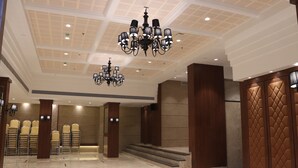 Un vestíbulo de hotel con techo alto, candelabros, una zona de estar con sillas y una escalera.