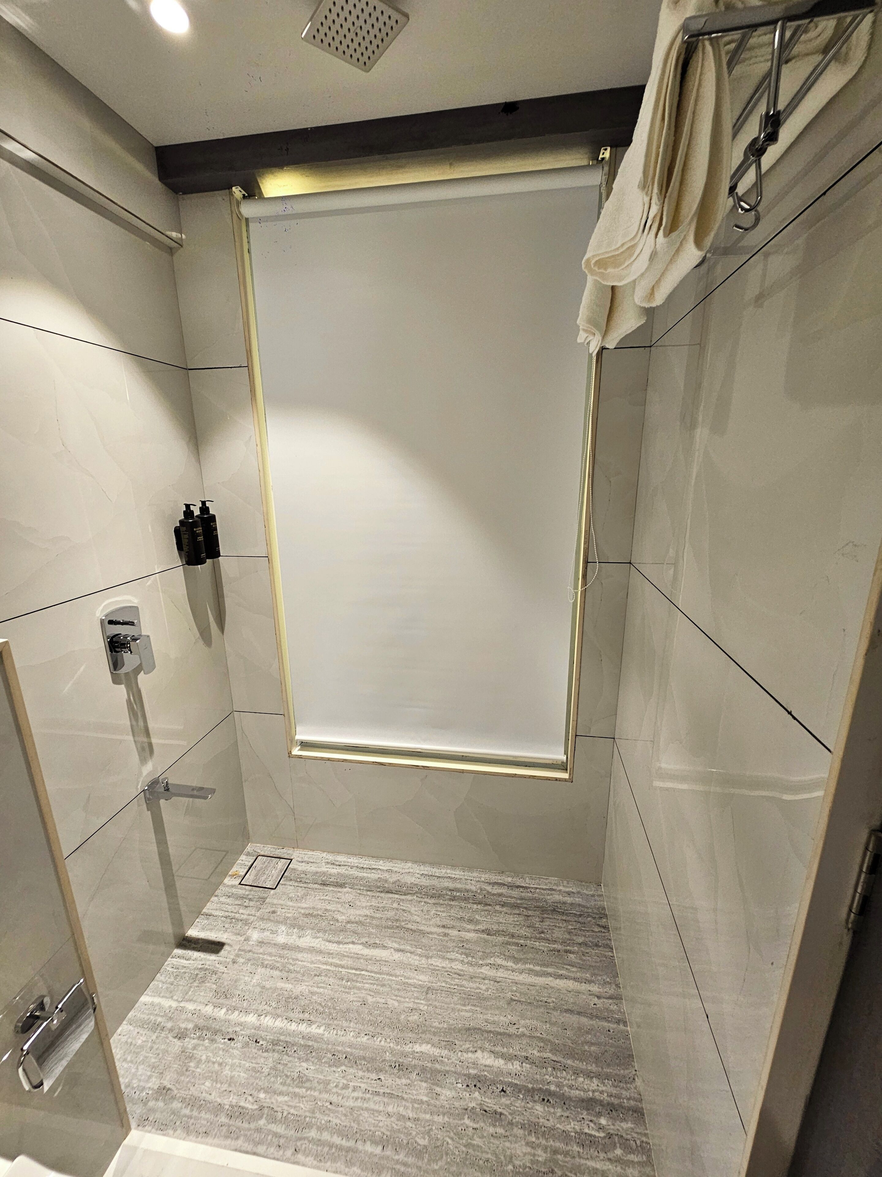 A modern shower area with a glass door, a towel rack, and a shower control panel.