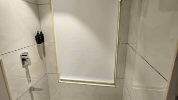 A modern shower area with a glass door, a towel rack, and a shower control panel.